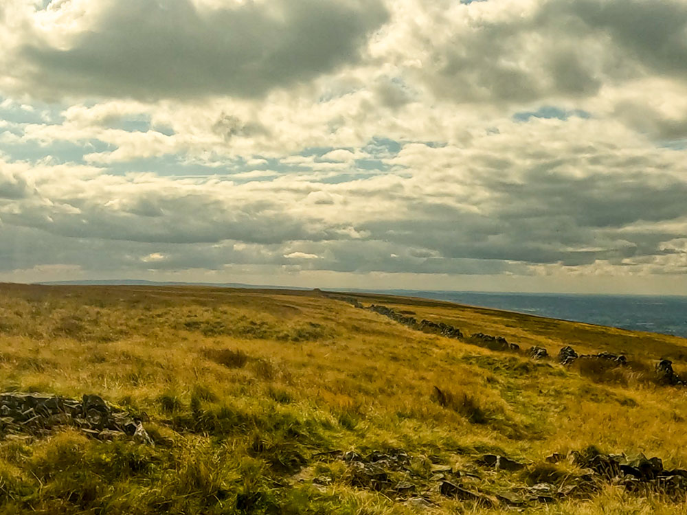 Passing over the tumbled-down wall, the path heads on along the left-hand side of the next wall over Mearley Moor