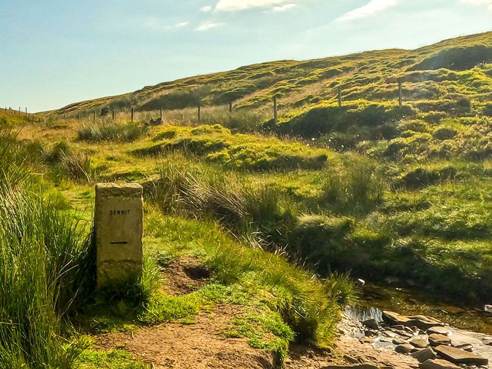 The stone waymarker that directs you over the stream towards the summit of Pendle Hill